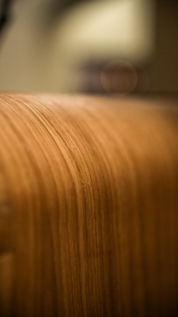 Gesloten houten deur met verticale houtnerf in warm licht, wazig op de achtergrond.